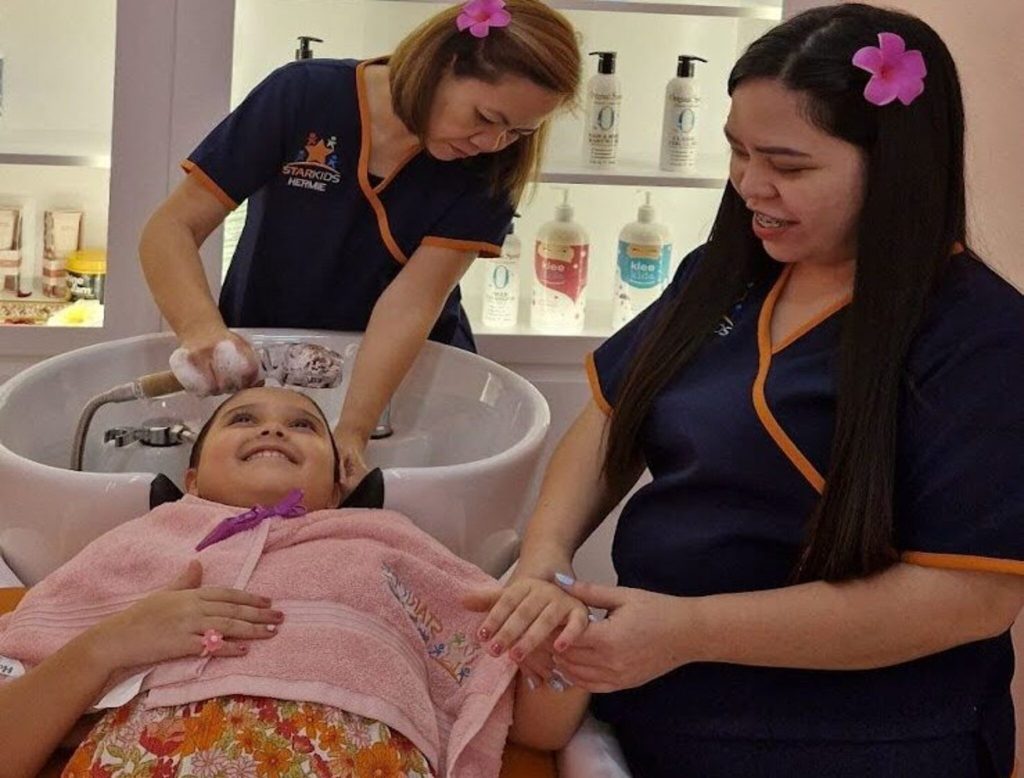 Stylist using safe hair care products for kids at StarKids Salon Dubai