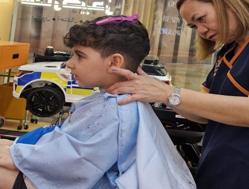 Happy boy getting a fun haircut at StarKids Salon in Dubai